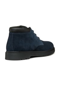 Stivaletti alla caviglia in suede blu navy con una collarino in pelle nera, punta tonda e suola piatta in gomma. Presentano un design con lacci e una superficie testurizzata.