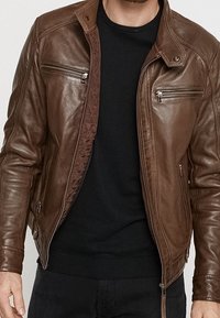 Brun læderjakke med ståkrave, lynlåslukning foran og lommer, med teksturerede sidepaneler og ribstrikkede manchetter.