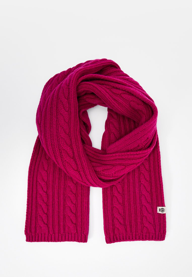 Fuchsia Kabelstrickschal aus weichem Material, mit strukturierten Zöpfen, gerippten Kanten und einem gewebten Etikett an einem Ende.