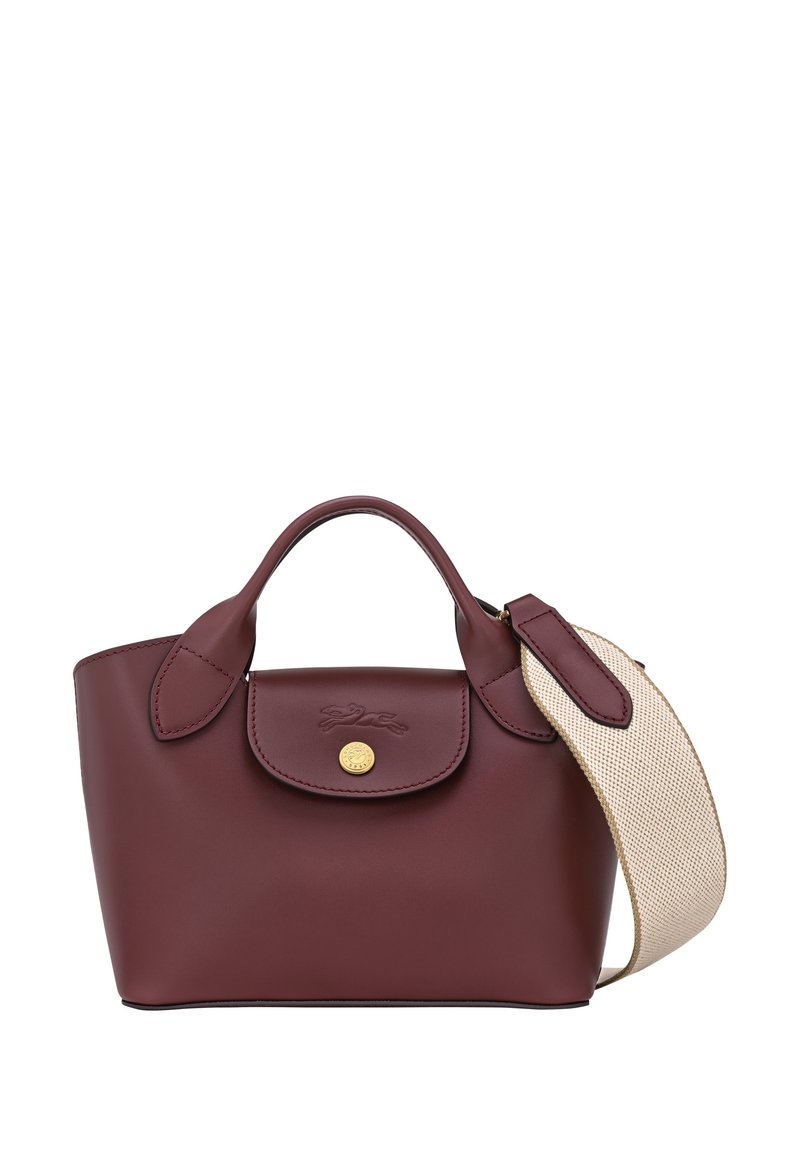 Burgundy leather handbag featuring a rounded shape, dual handles, and a textured cream strap. Gold hardware accents complete the design.