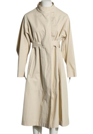 Beiger langer Trenchcoat mit hohem Kragen, langen Ärmeln, tailliertem Gürtel, seitlichen Taschen und asymmetrischem Frontverschluss an einer Schaufensterpuppe.