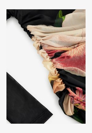 Černá tkanina s květinovým vzorem průhledného překryvu; z jedné strany nařasená textura, z druhé strany hladký povrch, který ukazuje jemné barvy a detaily.