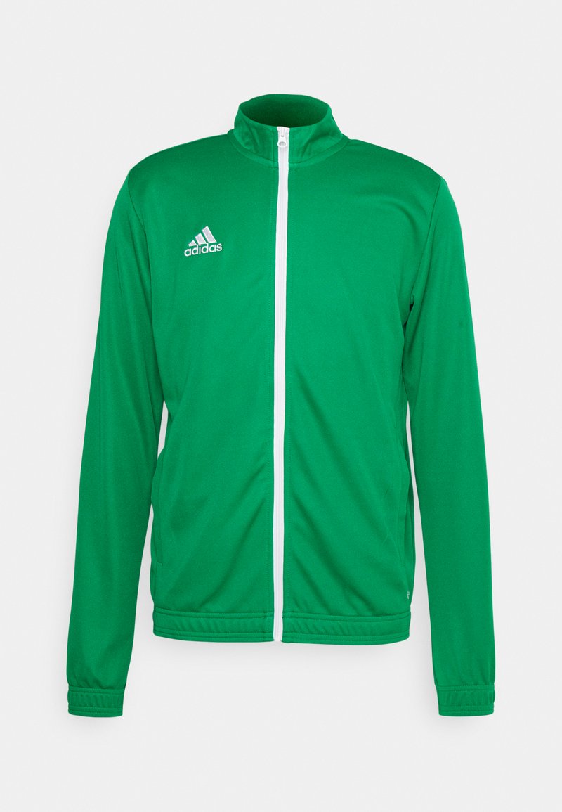 Grønn atletisk jakke med høy krage, hel glidelås foran og hvite detaljer. Har Adidas-logoen på venstre øverste side.