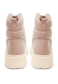 Botas tobilleras de encaje en suave cuero rosa, con una parte superior acolchada y una suela de goma crema texturizada con ranuras horizontales y detalles.