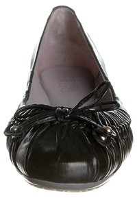 Svart läderballettsko med rynkad textur, rund tå och en dekorativ rosett. Mjuk inredning i kontrasterande färg.