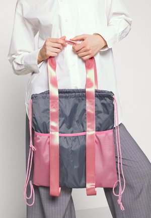 Mångfärgad axelväska gjord av nylon; har en grå överdel, rosa nederdel och rosa remmar; inkluderar dragsko-stängning och strukturerade accenter.