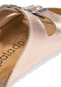 Sandal in metallo rosa con cinturino con fibbia, tomaia in pelle morbida, soletta in sughero e suola in gomma bianca. Interno testurizzato per il comfort.
