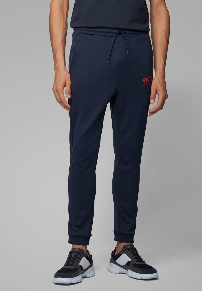 Námořnické tepláky z měkké bavlněné směsi, s nízkým pasem se šňůrkou, zužujícími se nohavicemi a červeným logem na levém stehně.