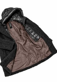 Zwarte buitenjack met een gestructureerde, fuzzy buitenkant. De binnenkant heeft een bruine voering en een glad, gewatteerd zwart capuchon. Met ritsluiting.