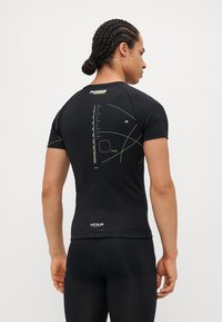 Camiseta deportiva negra de manga corta con acentos verdes y patrones geométricos en la parte posterior. Cuenta con un diseño ajustado y material liviano.