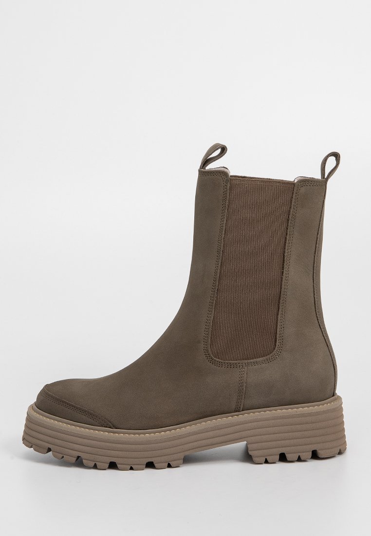 Braune Wildleder-Stiefelette mit elastischen seitlichen Einsätzen, runder Zehenpartie und dicker, geriffelter Sohle. Verfügt über einen Zugriegel hinten für einfaches An- und Ausziehen.