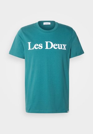 Teal cotton crew-neck t-shirt featuring "Les Deux" printed in large white letters across the chest. Short sleeves and straight cut.