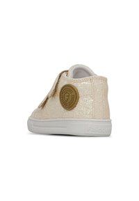Baskets Velcro en matériau pailleté pâle, avec un patch logo rond, une semelle en caoutchouc blanc et une texture lisse.