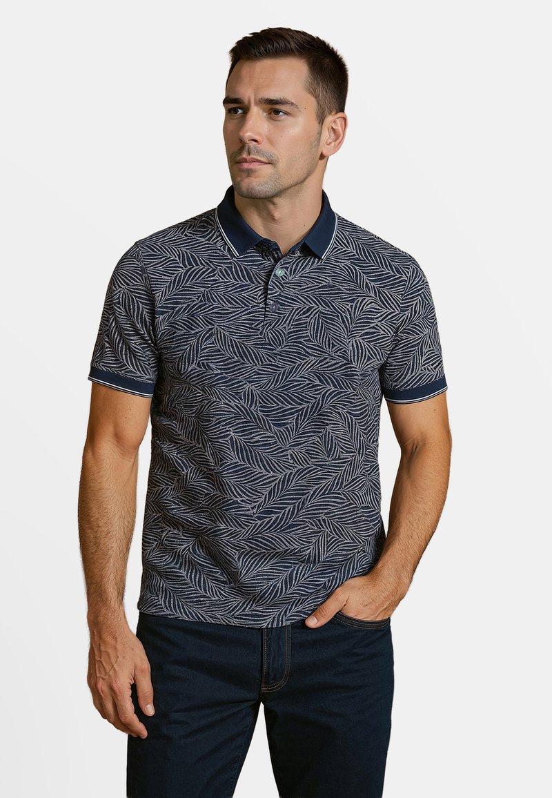 Marineblauwe polo met een wit bladdessine, korte mouwen en een contrasterende kraag. Gladde textuur en slim fit. Minimaal accent.