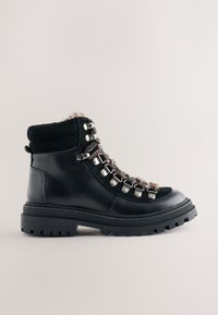 Black leather hiking boot with a textured wool collar, metal eyelets, and a rugged rubber sole featuring pronounced treads for traction.