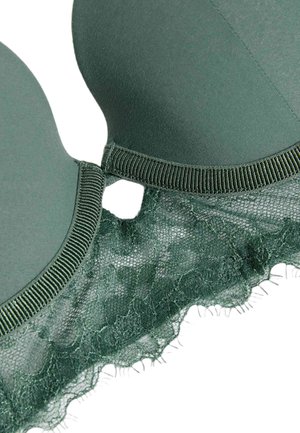 Reggiseno verde con coppe in tessuto morbido, rifiniture in pizzo con motivo floreale e un dettaglio intagliato decorativo al centro. Bordatura texturizzata.