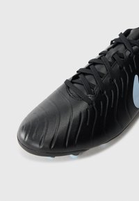 Black soccer shoe with a textured leather upper, curved shape, and contrasting light blue accents on the sole. Features laces for closure.