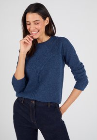 Maglione azzurro a maglia con motivo a diamante testurizzato e maniche a 3/4, abbinato a jeans in denim scuro. Tessuto liscio, vestibilità casual.