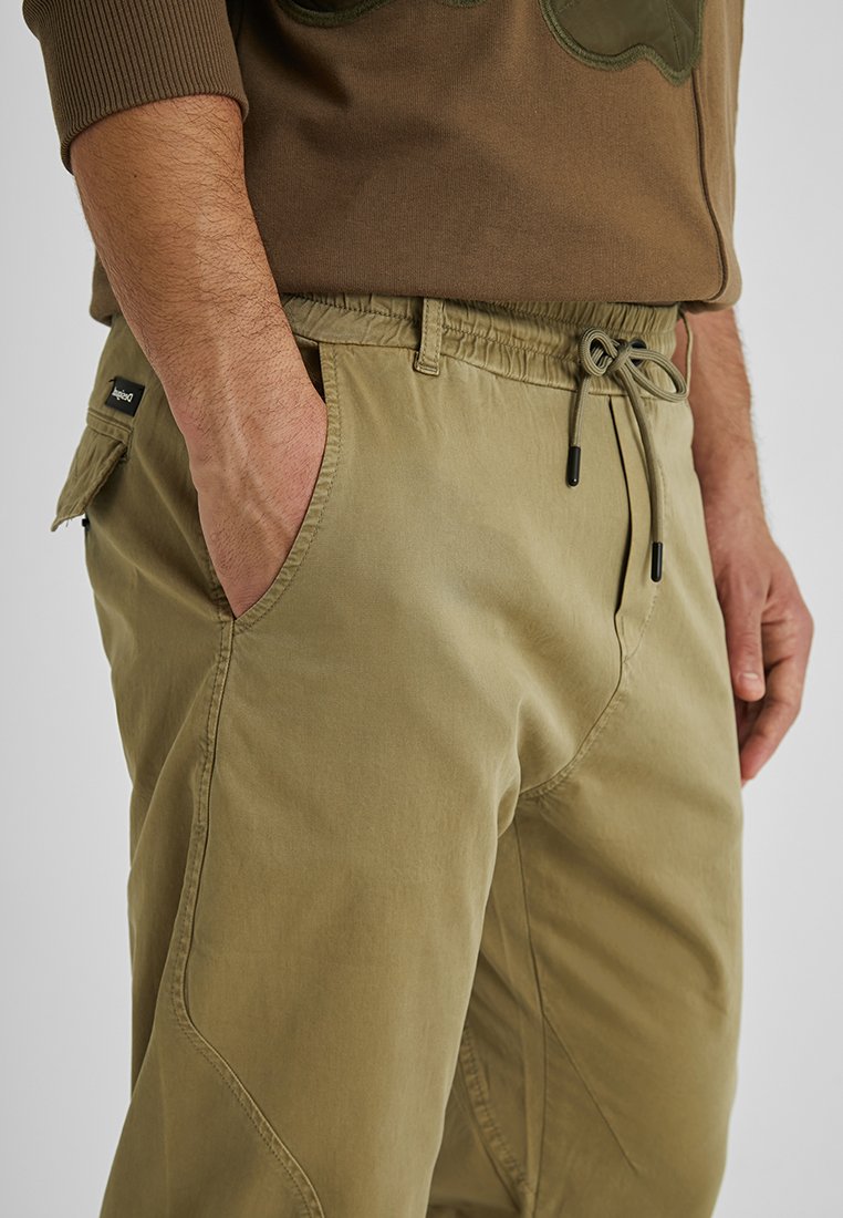 Helle khaki Stretchhose mit einem elastischen Bund, Kordelzug, Seitentasche und glatter Textur, mit schrägen Nahtdetails.