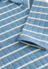 Polo en maille bleu avec des rayures horizontales blanches, présentant un motif texturé et un col structuré. Tissu doux avec des poignets côtelés.