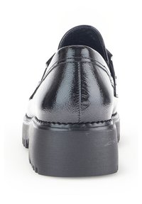 Black patent leather shoe with a rounded toe, raised heel, and textured sole. Features stitching along the back and a smooth finish.