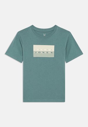 Kortärmad T-shirt i teal med rund hals och rektangulärt märke på bröstet med texten "JACK & JONES" i krämfärg och mörkblått.