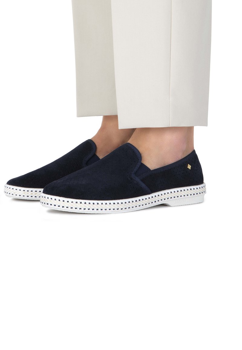 Navy suède instapschoenen met perforaties, witte rubberen zool en decoratieve stiksels langs de rand. Rondneus design.