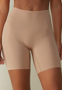 Beige vormgevende shorts van rekbaar materiaal; hoge taille; zachte textuur; knie-lengte met vlakke naden voor comfort.
