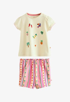 Kremasta majica kratkih rukava za malu djecu s vezom tropskih motiva i ružičaste elastične hlače s višebojnim prugama i uzorcima ananasa.
