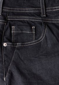 Mörkblå denimbyxor har en bakficka med kontrasterande gul sömnad, en metalldetalj och en slät yta.