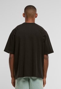 Sort bomulds oversized t-shirt med korte ærmer, rund hals og lige afslutning. Glat tekstur, minimalistisk design og ingen synlige logoer.