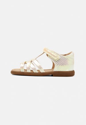 Iridescente platte kindersandaal met slangenprint bandjes en een bruine zool, voorzien van een klittenbandsluiting rond de enkel.