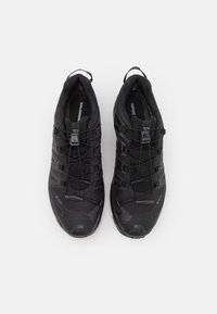 Black athletic shoes featuring a textured synthetic upper, elastic laces, reinforced toe cap, and a cushioned insole with brand logo.