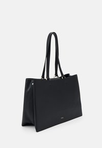 Sac fourre-tout en cuir noir avec deux longues poignées, design minimaliste, forme rectangulaire, détail logo doré en bas, texture lisse.