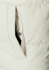 Light beige puffer jacket fabric with a side pocket featuring a snap button closure. Smooth texture and minimalistic design.