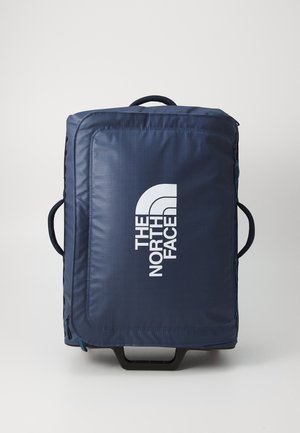 Valigia rotolante blu navy con finitura texturizzata, caratterizzata da un logo bianco prominente, maniglia superiore e zip laterale per un facile accesso.