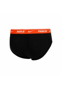 Bóxers negros de Nike con una amplia cinturilla naranja que presenta logotipos y símbolos de swoosh blancos de Nike espaciados uniformemente.