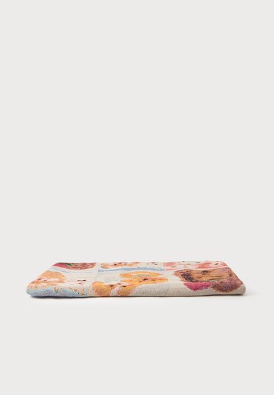 Tapis rectangulaire en tissu plié avec un motif patchwork coloré comportant des oursons sur fond clair, présenté sur surface blanche.