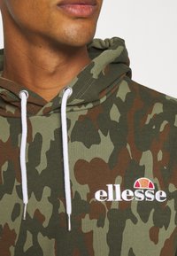 Bluza z kapturem w zielonych odcieniach z białymi sznurkami i srebrnymi metalowymi akcentami. Posiada wyhaftowane logo „ellesse” i miękką fakturę.