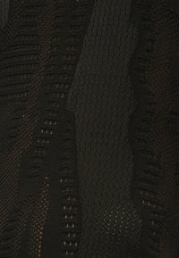 Μαύρος υφασμάτινος ιστός με αφηρημένο μοτίβο που διαθέτει ποικιλία πλεκτών στυλ και υφαντών τμημάτων, δημιουργώντας βάθος και οπτικό ενδιαφέρον.