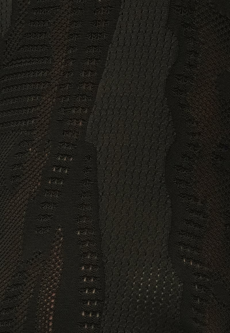 Tissu noir texturé présentant un motif abstrait avec des styles de tricot variés et des sections tissées, créant profondeur et intérêt visuel.