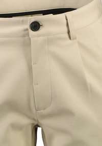 Beige trousers made of textured fabric with a button closure, featuring a flat front and side pockets for a clean, tailored look.