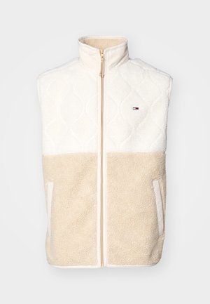 Mouwloos fleecevest met kleurvlakken in crème en beige, doorgestikte bovenkant, volledige ritssluiting aan de voorkant en zijzakken.