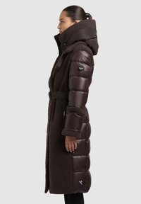 Pruun sulejope pehme välimusega. Varustatud kõrge krae, vöö, külgseeluku ja varrukal asuva brändilogoga. Tekstuurse ja pika lõikega.