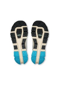 Sportschoenen met een zwart-blauwe rubberen loopzool, voorzien van een textuurpatroon en een beige tussenzool. Ontworpen voor grip en stabiliteit.