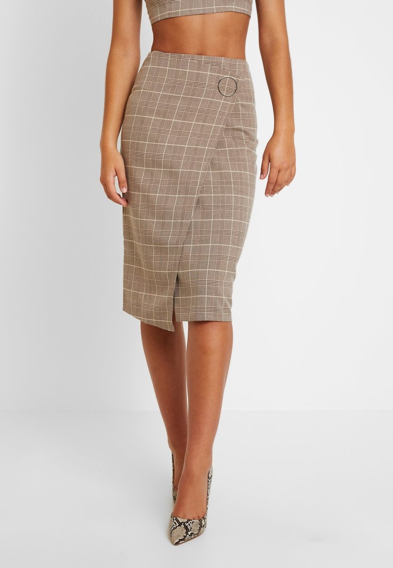 Jupe crayon à carreaux marron avec fente latérale, ornée d'un accent circulaire et d'une coupe ajustée. Fabriquée en tissu texturé avec des lignes horizontales et verticales.