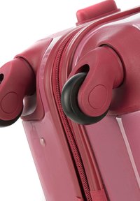Valise rigide de couleur rose foncé, dotée d'une surface lisse, de deux roues et d'un zip contrastant.