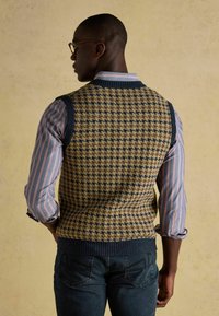 Koonitud vest, millel on houndsatõugimuster, kollane ja tume sinine; ribadega kaelus ja alumine äär. Ühendatud triibulise särgi ja üles keeratud mansettidega. Tumedad sinised teksad.