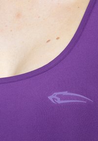 Lila linne med rund halsringning och en slät, mjuk yta. Märkbart ljusare logotyp på vänster sida.