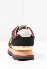 Sneaker nera in suede con stampa leopardo, dettagli bordeaux, tacco in argento metallico e suola in gomma testurizzata. Vista posteriore che mette in evidenza le caratteristiche del design.